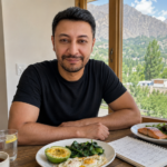 Shahbaz Ahmed founder of KetoFramework in a black crew neck at his Gilgit-Baltistan dining table with a two-meal eating window spread including eggs avocado salmon and leafy greens and a weekly meal plan notepad smiling directly at camera representing the intermittent fasting meal plan and what to eat on intermittent fasting every day