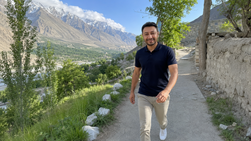 Shahbaz Ahmed founder of KetoFramework in a navy polo shirt walking confidently outdoors in the Gilgit-Baltistan mountain landscape looking directly at camera with a broad energetic smile representing the benefits of a keto diet plan including fat loss stable energy and metabolic health improvements